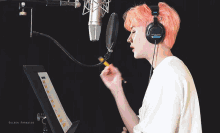 a man with pink hair is singing into a microphone with the words golden paradise written below him