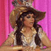 a woman wearing a hat with a tiger on it is sitting in front of a pink curtain