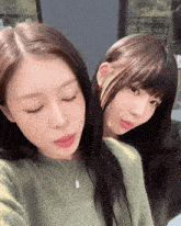 two girls are posing for a picture and one is wearing a necklace