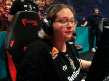 a woman wearing headphones and a black shirt with red bull on it