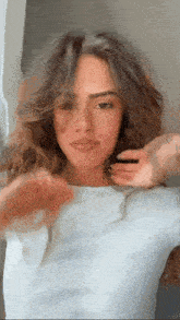 a woman with long brown hair is wearing a white shirt and a necklace