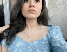 a woman wearing a blue top and a heart necklace