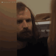 a man with long hair and a beard is peeking through a door with the hashtag #diggstown