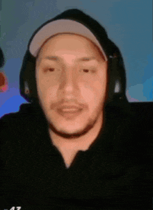 a man wearing headphones and a hat is looking at the camera .