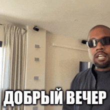 a man wearing sunglasses is standing in a room with the words " добрый вечер " on the bottom right