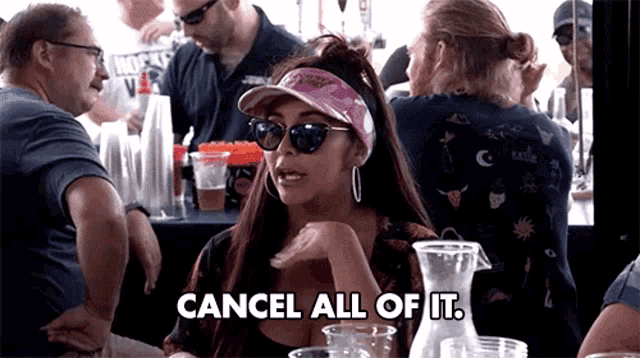 a woman wearing sunglasses says cancel all of it while sitting at a table