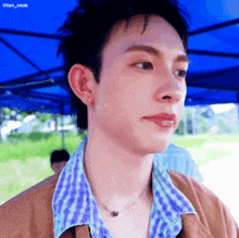 a close up of a man 's face with a blue tent in the background