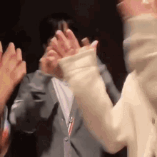 a group of people are clapping their hands in a room .