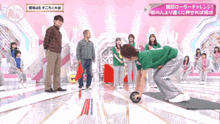 a woman in a green shirt rolls an exercise ball on a stage