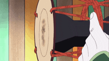 a cartoon drawing of a hand holding a drum with red ropes