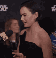 a woman speaking into a mtv microphone in front of a star wars sign