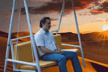 a man sitting on a swing in the desert