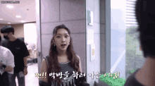 a woman talking to a man in a hallway with korean writing