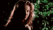 a young girl with long hair is sitting on a swing in the dark .