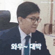 a man in a suit and tie is sitting in a chair and making a face .