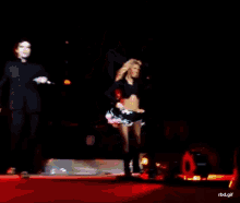 a woman is dancing on a stage with a man behind her