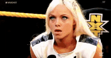 a woman with blonde hair is standing in a wrestling ring and making a funny face .