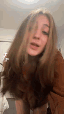 a woman with long hair is standing in front of a bed in a room .