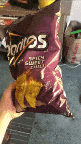 a person holding a bag of doritos spicy sweet chili chips