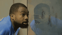 a man with a beard is looking at his reflection in a glass