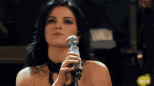 a close up of a woman singing into a microphone with rbd.gif in the corner