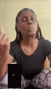 a woman blowing a kiss while sitting in front of a cell phone