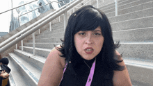 a woman wearing a lanyard that says ' nbc ' on it stands in front of a set of stairs