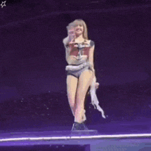 a woman is standing on a stage holding a microphone and waving .