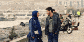 a man and a woman are walking down a sidewalk talking to each other
