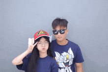 a boy wearing sunglasses and a girl wearing an arale hat pose for a photo