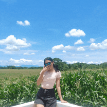 a woman wearing sunglasses is sitting in front of a field