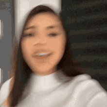 a blurry picture of a woman wearing a white sweater and a white hat .