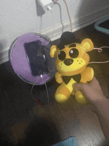 a person holding a stuffed freddy bear next to a cell phone