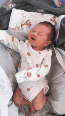 a baby wearing a white bodysuit with a pumpkin on it