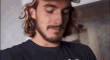 a man with long hair and a beard is looking down