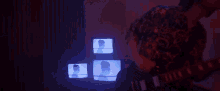 a man is playing a guitar in front of three television screens .