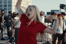 a woman in a red shirt is dancing in front of a crowd of people
