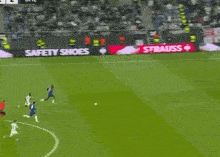 a soccer game is being played on a field with a strauss advertisement on the sidelines