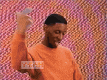a man wearing an orange sweater says yeah