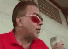 a man wearing red sunglasses and a red shirt is talking to someone .