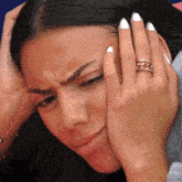 a woman with a ring on her finger has her hand on her head