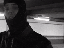 a man wearing a ski mask is standing in a parking garage .