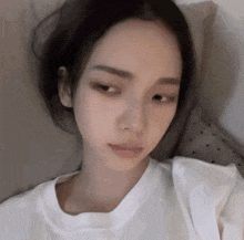 a woman in a white t-shirt is laying on a bed