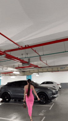 a woman in a pink dress is walking in a parking garage with a sign that says b-119