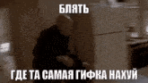 a man is sitting on the floor in front of a refrigerator in a room with russian writing on it .