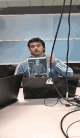 a man sitting at a desk holding a picture of a man named php lore