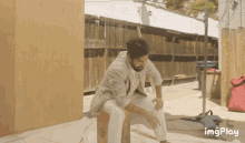 a man is sitting on a cardboard box with the hashtag imgplay on the bottom