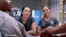 two female firefighters are talking to a man in an ambulance with the hashtag chicagofire on the bottom