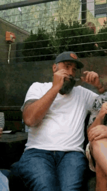 a man with a beard wearing a hat and a white shirt