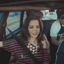 a woman in a striped shirt is sitting in a car with other people .